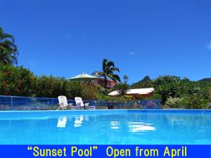an empty swimming pool with chairs and an umbrella at Beach Village Nosoko in Ishigaki Island