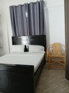 a bedroom with a bed with a black headboard and a chair at Hidalgo Explorers Home in Moshi