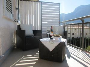 a table with wine glasses and a chair on a balcony at Le Dimore di Enea in Castellammare del Golfo