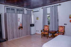 a bedroom with a bed and two chairs and a table at PEACE GUEST HOUSE in Yaoundé