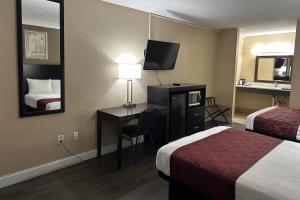 a hotel room with two beds and a desk with a television at Rodeway Inn Bushnell in Bushnell +22 photos