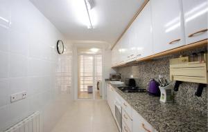 a kitchen with white cabinets and a clock on the wall at Gorgeous Apartment In Calafell With Swimming Pool in Calafell