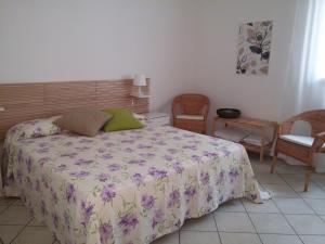 a bedroom with a bed with a floral bedspread and chairs at Akron B&B in SantʼAlessio Siculo