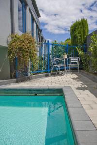 a swimming pool with a table and chairs next to a house at Clearwater Motor Lodge in Taupo