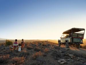 two people sitting in chairs next to a military vehicle at Aardvark Bioreserve in Ladismith