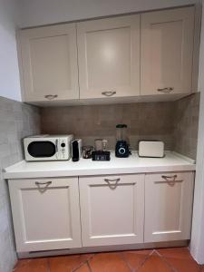 a kitchen with white cabinets and a microwave at CharmandView Assisi - vista unica su Basilica di Santa Chiara con terrazza panoramica esclusiva nel centro storico in Assisi