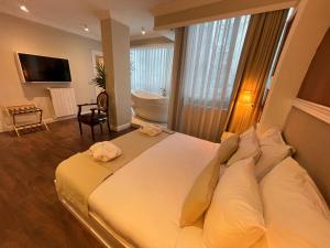 a bedroom with a large bed and a bathroom with a tub at DBD Hotel Bayraklı in Bayrakli