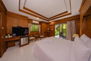 a bedroom with a large white bed and a television at Sand Sea Resort Railay Beach in Railay Beach