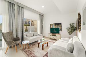 a living room with two couches and a tv at FIRST CLASS Villa Peaceful Pool View Retreat in Dubai
