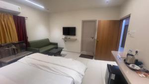 a hotel room with a bed and a green chair at Sithara Grand in Ongole