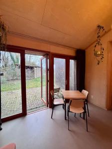 a dining room with a table and chairs and a window at Bed & Coffee Skilleplaatsje in Den Burg