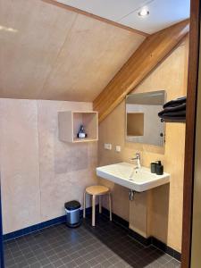 a bathroom with a sink and a stool at Bed & Coffee Skilleplaatsje in Den Burg