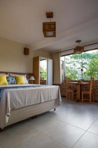1 dormitorio con 1 cama, mesa y sillas en Pousada Areias do Rosa, en Praia do Rosa