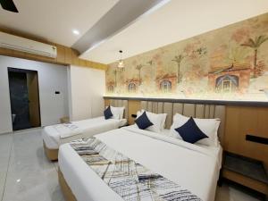 two beds in a room with a painting on the wall at White Panda hotels Shree Radhe in Dwarka