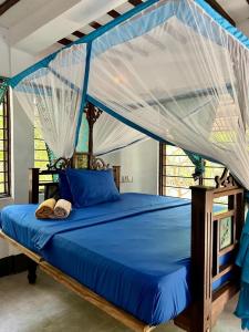 a bedroom with a blue bed with a canopy at Embe Lodge in Kizimkazi