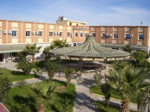 a large building with a courtyard with palm trees in front of it at Motel Paris Dakar in Selouane