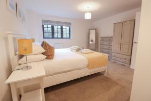 a bedroom with a bed and a lamp on a table at Corner Cottage, Thorpeness in Thorpeness