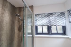 a shower with a glass door and a window at Corner Cottage, Thorpeness in Thorpeness