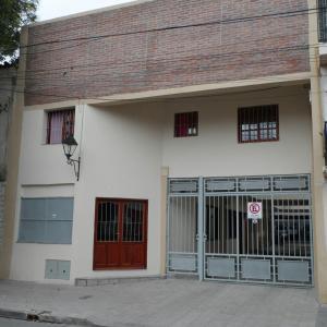 a white building with a red door and a gate at Alquiler Temporario Salta in Salta