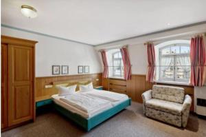 a bedroom with a bed and a chair and windows at Gästehaus Blaue Ecke in Adenau