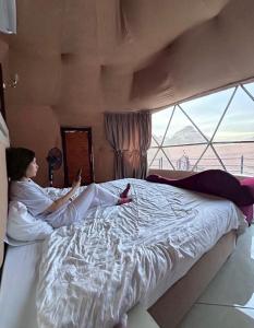a woman laying on a bed looking at her cell phone at Omar Ghazi Camp in Wadi Rum