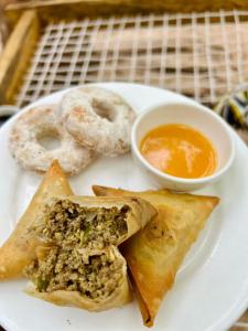 a plate of food with doughnuts and a bowl of dipping sauce at Embe Lodge in Kizimkazi