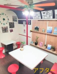 a room with two white tables and red stools at 高松guesthouseOLD in Takamatsu