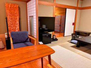 a living room with a table and a chair at Yufuin Santoukan in Yufu