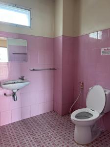 a pink bathroom with a toilet and a sink at โรงแรมสิริพรชัย in Takua Pa