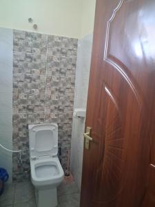 a bathroom with a toilet and a wooden door at PAZURI - Homes in Voi +33 photos