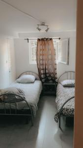 a bedroom with two twin beds and a window at Rez chaussée transformé en t4 au 114 Avenue de juvisy cottages in Juvisy-sur-Orge
