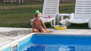 a young child sitting next to a swimming pool at Guest House Ongal in Krushuna