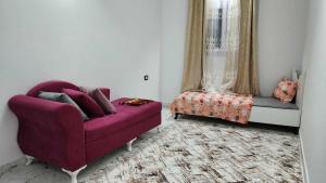a living room with a purple couch and a chair at Studio Bayen in Douz