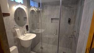 a bathroom with a shower with a sink and a mirror at The Pinus Resort in Pahalgām