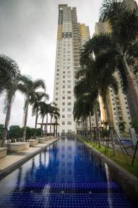 a swimming pool with palm trees in front of a building at Luxe320 at On320 Residencies in Colombo