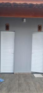 two white garage doors on a white wall at Rancho Duarte in Itanhaém