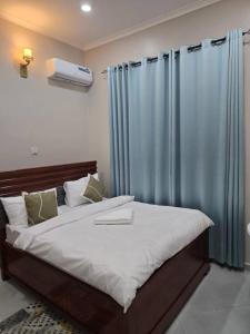 a bedroom with a large bed with blue curtains at Kibs Apartments in Dodoma