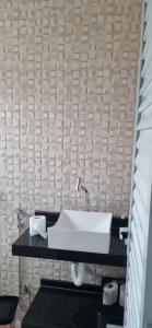 a bathroom with a white sink on a black counter at Rancho Duarte in Itanhaém