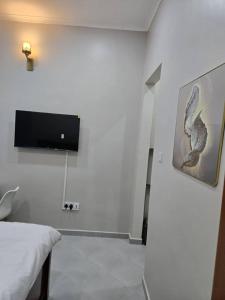 a white room with a tv on a wall at Kibs Apartments in Dodoma