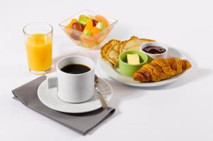 a cup of coffee and a plate of breakfast food at Kyriad Blois Nord in Blois