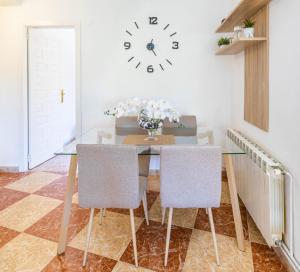 a dining room table with chairs and a clock on the wall at Paraíso Familiar en Marisol Park Bungalow con Piscina, Tenis y Parking in Calpe