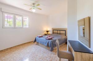 a bedroom with a bed and a table and windows at Paraíso Familiar en Marisol Park Bungalow con Piscina, Tenis y Parking in Calpe +25 photos