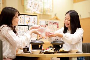 two women sitting at a table eating food at Pioland Hotel in Saitama