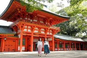two women walking in front of an orange building at Pioland Hotel in Saitama
