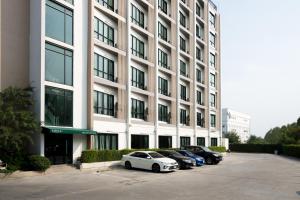 a group of cars parked in a parking lot in front of a building at Mayuu Ayutthaya Hotel in Ban Ko Rian