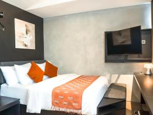 a bedroom with a bed and a flat screen tv at Maisola by ARTOTEL Semarang in Semarang