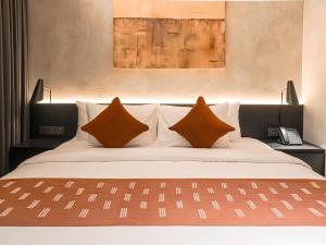 a bedroom with a large bed with two pillows at Maisola by ARTOTEL Semarang in Semarang