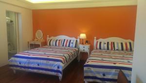 a bedroom with two beds and an orange wall at Jiufen Golden House in Jiufen