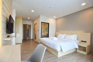 a bedroom with a large white bed and a television at Mayuu Ayutthaya Hotel in Ban Ko Rian
