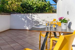 a wooden table with yellow chairs on a patio at Vogelmaierhof am Kalterer See in Caldaro